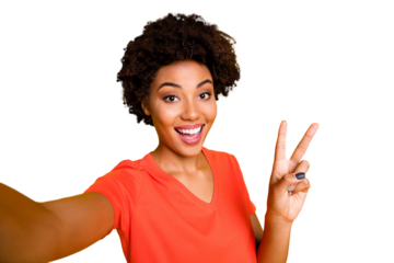 Self photo of cheerful charming pretty curly wavy girlfriend showing you v-sign recording video taking selfie influencing her audiences wearing orange t-shirt isolated yellow vivid color background