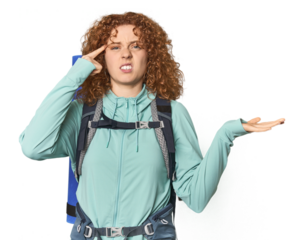 Young Caucasian redhead ready for hiking holding and showing a product on hand.