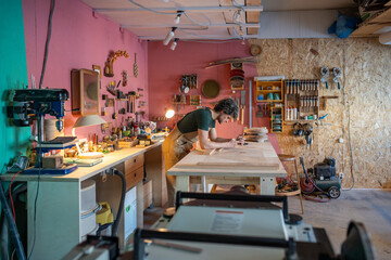 Focused woodworker checks order specifications on smartphone while organizing workshop materials....