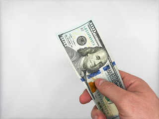 Male white hand holding 100 dollars to bribe policeman on white background top view