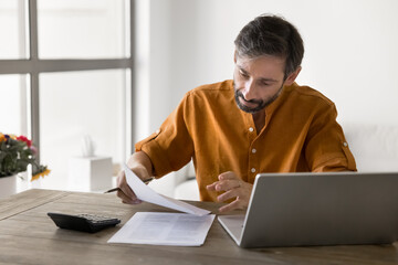 Finance paperwork. Focused busy mature businessman entrepreneur working at home office engaged in...