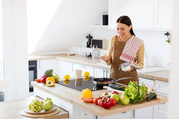 Young woman cooking, seasoning meat with salt frying in a pan, preparing tasty dinner, free space