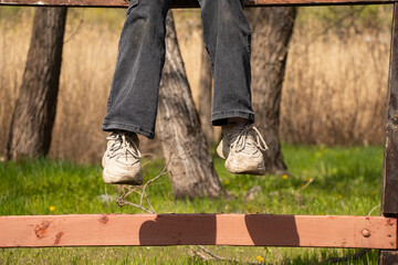 Legs of a girl sitting on a fence in a pair in the spring in Ukraine, outdoor recreation