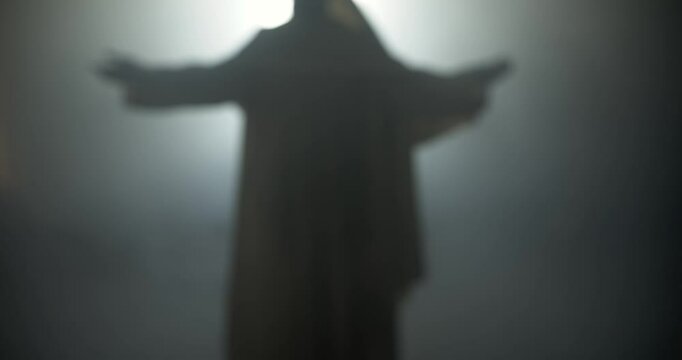 Silhouette of resurrection of Jesus Christ inside the tomb, in bright light, raising his hands in dramatic, cinematic slow motion. Perfect for Easter resurrection visual.