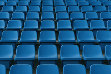 Symmetrical blue plastic stadium seats under soft diffused daylight atmosphere