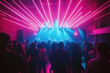 Naklejka premium A vibrant concert crowd enjoys the electrifying music and neon lights in a brick-walled venue.