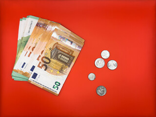 US cents and euro banknotes with denominations of 50 and 100 lie next to each other on a bright red...