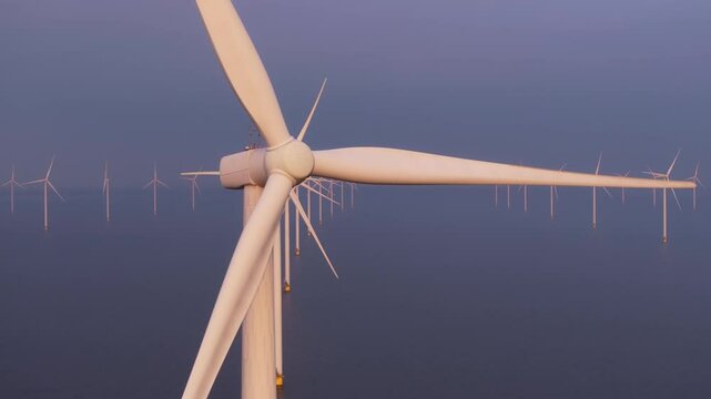 Offshore wind farm spinning above blue waters Netherlands. Aerial drone video