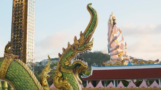 Close-up of green golden Naga serpent statue with the Guanyin sculpture, Buddhist Goddess of Mercy and Compassion with eighteen arms on background in Wat Plai Laem temple on Samui island in Thailand