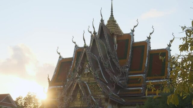 Thai Buddhist temple Wat Plai Laem with intricate golden roof details and dragon statues on Koh Samui island in Thailand with sun flare at sunset. Travel and touristic landmark