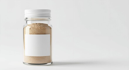 A clear glass jar filled with a light brown powder, featuring a blank white label. The minimalist composition highlights the product against a clean, white background