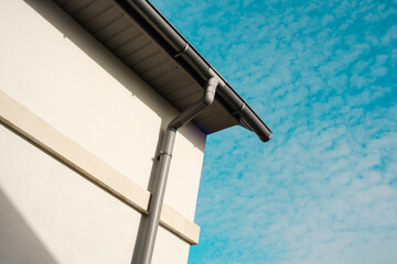 Modern building corner with drainage pipe against a beautiful sky backdrop