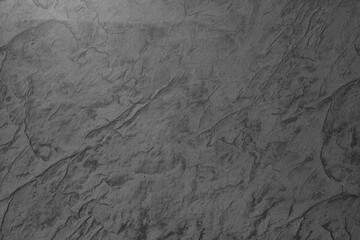 Dark textured surface with intricate patterns and natural variations revealed