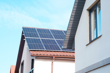 Fototapeta premium Solar panels installed on houses in a residential area with clear blue skies