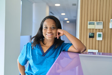Smiling dentist leaning on reception desk in dental clinic