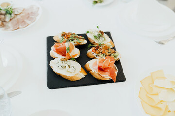 Tasty variety of bruschetta served on a black slate platter at a gathering