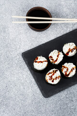 Sushi rolls with cream and sauce on a slate plate in a modern setting