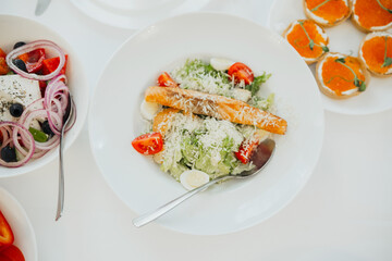 Fresh salad with salmon and tomatoes served at a sunny outdoor table