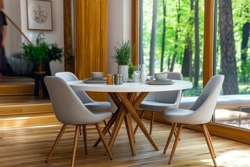 Obraz premium Modern Scandinavian dining room with round white table, grey chairs with natural wood legs, and natural light from the window.