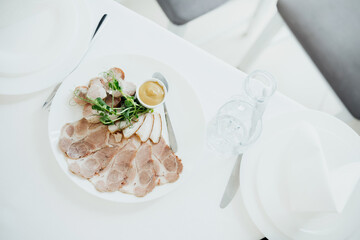 Delicious meat platter with fresh herbs and sauce on a dining table