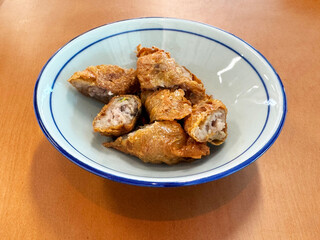 traditional asian deep fried crispy golden chicken wu xiang meat vege roll appetiser in white bowl on wood table chinese dim sum snack cafe halal menu food restaurant