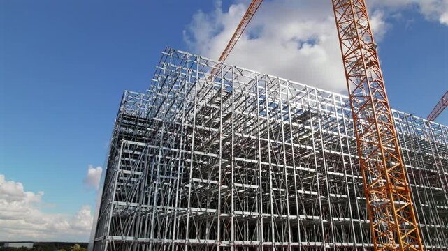 Arcing Drone Shot of Large Building Being Constructed by Cranes and Heavy Machinery