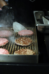 chef asando hamburguesas de carne a la parrilla con una paleta de cocina