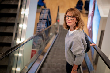 Blond haired female using the eschalator in a shopping mall