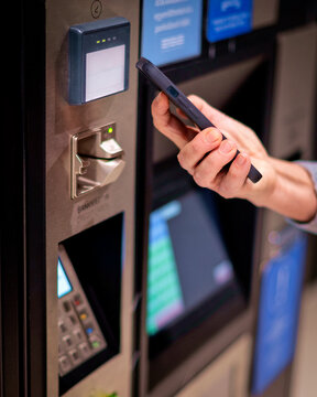 Close-up of a woman&rsquo;s hand holding cell phone in her hand and paying the parking fee by phone