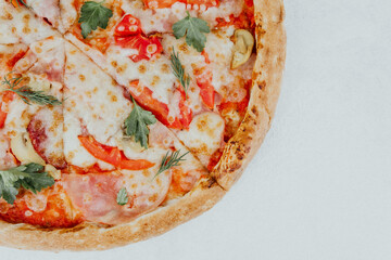 Freshly baked pizza topped with cheese, peppers, and herbs on a white background