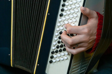 Close-up of a musician's hand playing a traditional accordion, showcasing the intricate details of the instrument and the skill involved in creating music