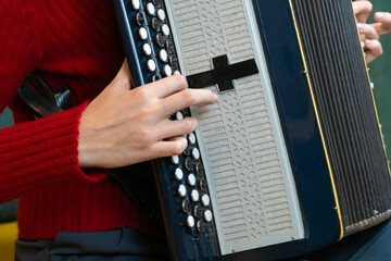 Close-up of a musician's hands playing a traditional accordion, showcasing the intricate details of...