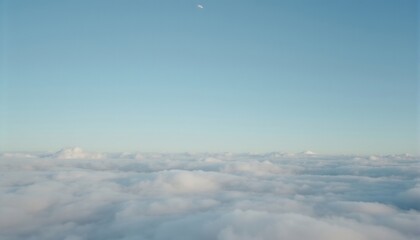 Above the Clouds: A serene high-altitude view of a vast expanse of fluffy white clouds stretching to the horizon under a pale blue sky, with a sliver of moon visible.
