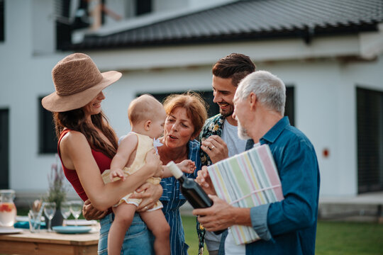 Parents welcoming their son, daughter-in-law, and baby at a family barbecue.