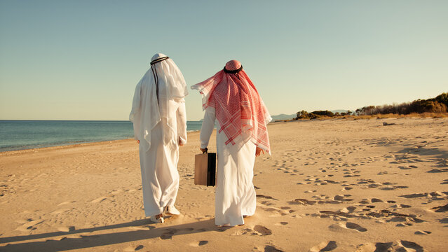 Two Sheiks Carrying A Briefcase In The Desert