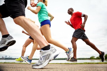 Naklejka premium People, fitness and running with legs in nature for outdoor workout, exercise or physical activity together. Athlete, runners or group with sprint for race, cardio training or health and wellness