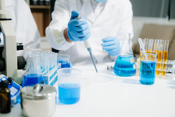 Two  scientists in a high-tech lab analyzing biochemical samples, using micro pipettes