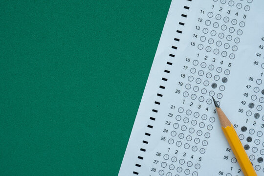 close up yellow pencil on answer sheets with green background, education concept