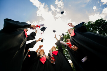 Low angle view portrait of group students hold diplomas throw air mortarboards graduation...