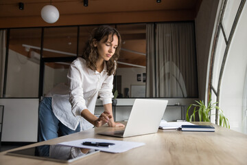 Confident focused business efficient CEO manager woman works managing tasks using her laptop and...