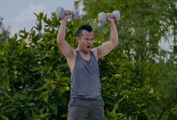 Shoulder workout and training. Asian man doing shoulder exercises using dumbbells.