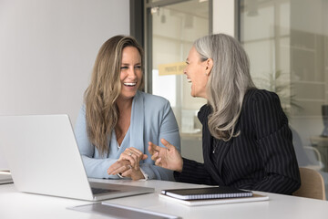 Professional fun. Happy laughing female colleagues office employees of diverse generations chatting...