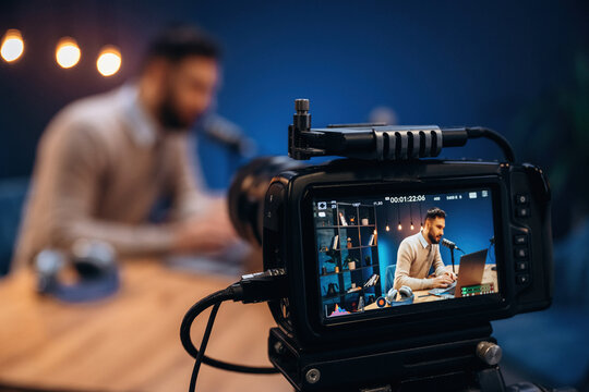 Camera is filming him. Man is on the radio doing podcast live