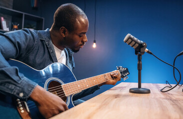 Obraz premium Singer songwriter with guitar. Man is doing podcast in the studio