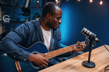 Obraz premium Playing acoustic guitar. Man is doing podcast in the studio