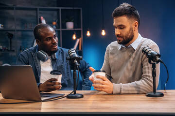 Cups of coffee in hands. Two radio presenters recording an audio broadcast in a studio