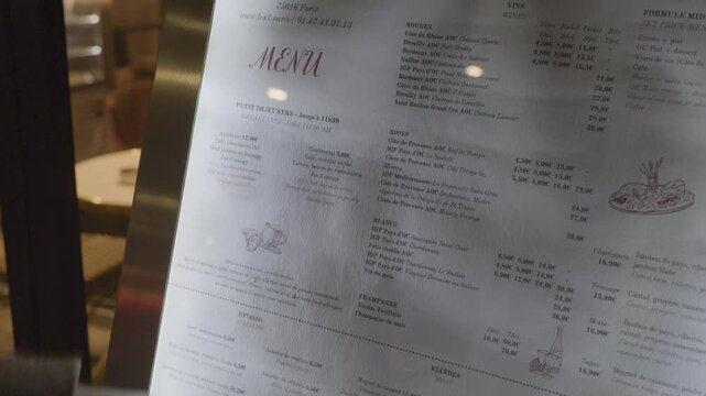 A hand pointing at a menu outside a caf&eacute; in Paris showcasing food options and beverages