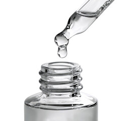 A transparent liquid is being carefully dropped from a pipette's tip into a small glass bottle. The focus is on the drop just before it enters the bottle opening