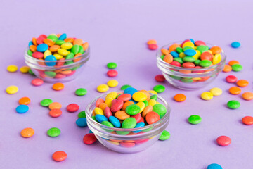 Multicolored candies in a bowl on a colored background. birthday and holiday concept. Top view with copy space
