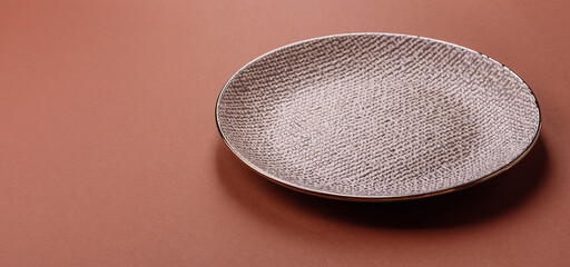 Empty ceramic plate on a monochrome brown background
